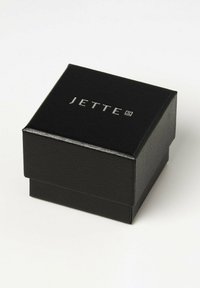 Schmuckkästchen in Schwarz mit Struktur und einem klappbaren Deckel, auf dem der silberne, geprägt eingestempelte Markenname "JETTE" zu sehen ist. Kompakte rechteckige Form.