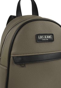 Mochila texturizada de color verde oliva con una cremallera negra, borde de cuero y un parche de marca que presenta "LOIS JEANS SINCE 1962" en blanco.