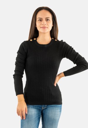 Suéter de punto negro con manga larga, escote redondo y botones decorativos color siena en los hombros. Combinado con jeans de mezclilla azules.