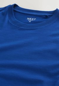 T-shirt bleu slim fit à col ras du cou en taille medium avec un col cousu et une étiquette de marque "NEXT" imprimée à l'intérieur du col.