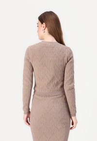 Strikket beige cardigan med et teksturert mønster, lange ermer, ribbestrikkede mansjetter og liv, med rund hals og design på ryggen.