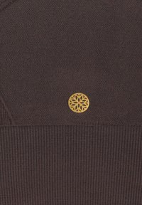 Braun gestricktes Kleidungsstück mit strukturiertem Finish. Verfügt über ein goldenes kreisförmiges Emblem mit einem floralen Design im Brustbereich.