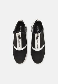 Scarpe sportive nere slip-on con una striscia bianca e dettagli con cerniera. Realizzate in tessuto a rete, presentano una superficie texturizzata e un logo sul lato.