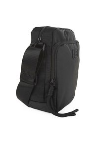 Bolsa de tela negra con un diseño acolchado, compartimentos con cremallera, correa ajustable y un logo texturizado. Forma compacta y rectangular.