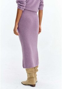 Długa lawendowa dzianinowa spódnica z dopasowanym paskiem i miękką fakturą. Połączona z beżowymi zamszowymi kozakami do kolan na słupku.