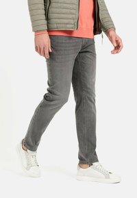 Grå denim jeans med slim fit og subtil tekstur, parret med hvide sneakers med grå accenter.
