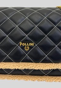 Borsa nera in pelle trapuntata con accento in finta pelliccia color crema, dettaglio del logo in oro e cuciture a contrasto. Forma rettangolare compatta.