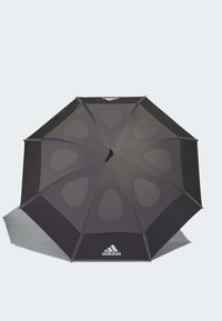 Black umbrella with eight panels, smooth texture, and cut-out shapes. Features an adidas logo and a central black handle.