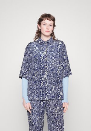 Blouse à manches courtes avec un motif tourbillon audacieux bleu marine et blanc, design col, associée à un pantalon assorti et des manches côtelées bleu clair.