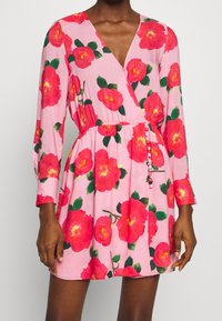 Florales Wickelkleid mit einem rosa Hintergrund und großen roten Rosenmustern, langen Ärmeln, tiefem V-Ausschnitt und tailliertem Bund mit Knopfdetails.