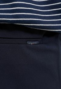 Tissu bleu marine avec une petite étiquette Jack & Jones près d'un tissu tricoté rayé bleu marine et blanc au bord supérieur.