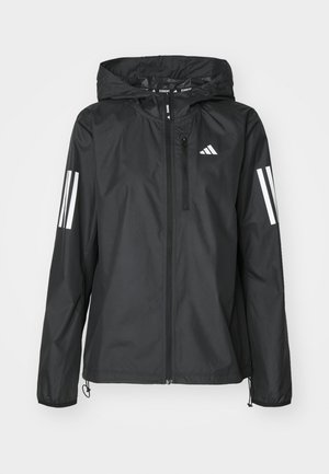 Schwarze leichte Jacke mit Kapuze, ausgestattet mit einem durchgehenden Reißverschluss und zwei weißen Streifen an jedem Ärmel. Glatte Textur, entwickelt für den Außenbereich.