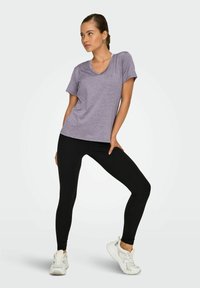 Kort ingekorte mouw, lavendel T-shirt met een V-hals, gecombineerd met zwarte leggings en witte sportschoenen. Soepele stof, relaxte pasvorm.