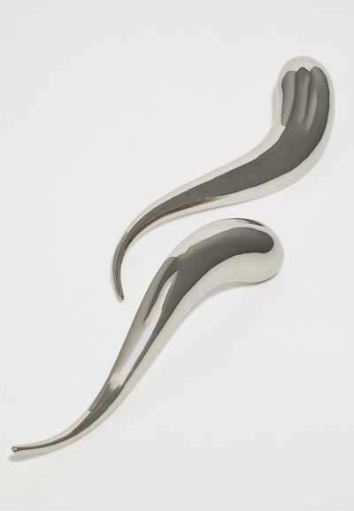Twee slanke,Reflecterende zilveren metalen sculpturen met langgerekte, gebogen vormen. Gladde textuur met ronde uiteinden en variërende breedschappen.