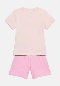 Ροζ ανοιχτόχρωμη κοντομάνικη μπλούζα συνδυασμένη με ροζ σορτσάκι με ελαστική μέση, παρουσιασμένα επίπεδα σε λευκό φόντο.