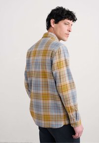 Camisa de cuadros con botones en tonos azules, amarillos y rojos, de corte relajado. Material de algodón con mangas largas y un collar clásico.