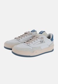 Sneakers bianchi in pelle e camoscio con accenti beige, punta arrotondata, dettagli perforati e suola beige leggermente elevata con accenti blu navy.