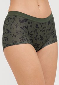 Tmavozelené dámske nohavičky s olivovo zeleným pásom, s čiernym botanickým vzorom listov a bobúľ na hladkej, elastickej látke.