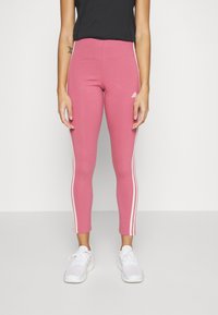 Pink leggings made of stretchy material, featuring white side stripes and an Adidas logo. They have a fitted, ankle-length design.