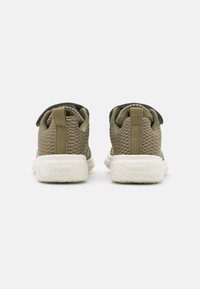 Un par de zapatillas de malla verde olivo con suelas blancas vistas desde la parte trasera, mostrando las lengüetas y el logo de la marca en las suelas.