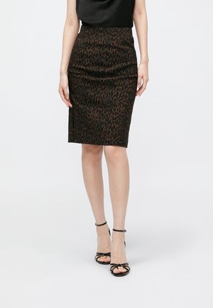 Jupe crayon imprimé léopard marron avec une coupe ajustée, longueur au genou, et un léger éclat. Associée à des talons noirs à brides.