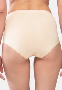 Högmidjade beige underkläder med mjuk textur, elastisk midja och inga synliga sömmar, designade för komfort och täckning.