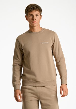Sudadera de algodón beige con mangas largas, puños y dobladillo acanalados. Presenta un logo sutil en el pecho y una textura suave.