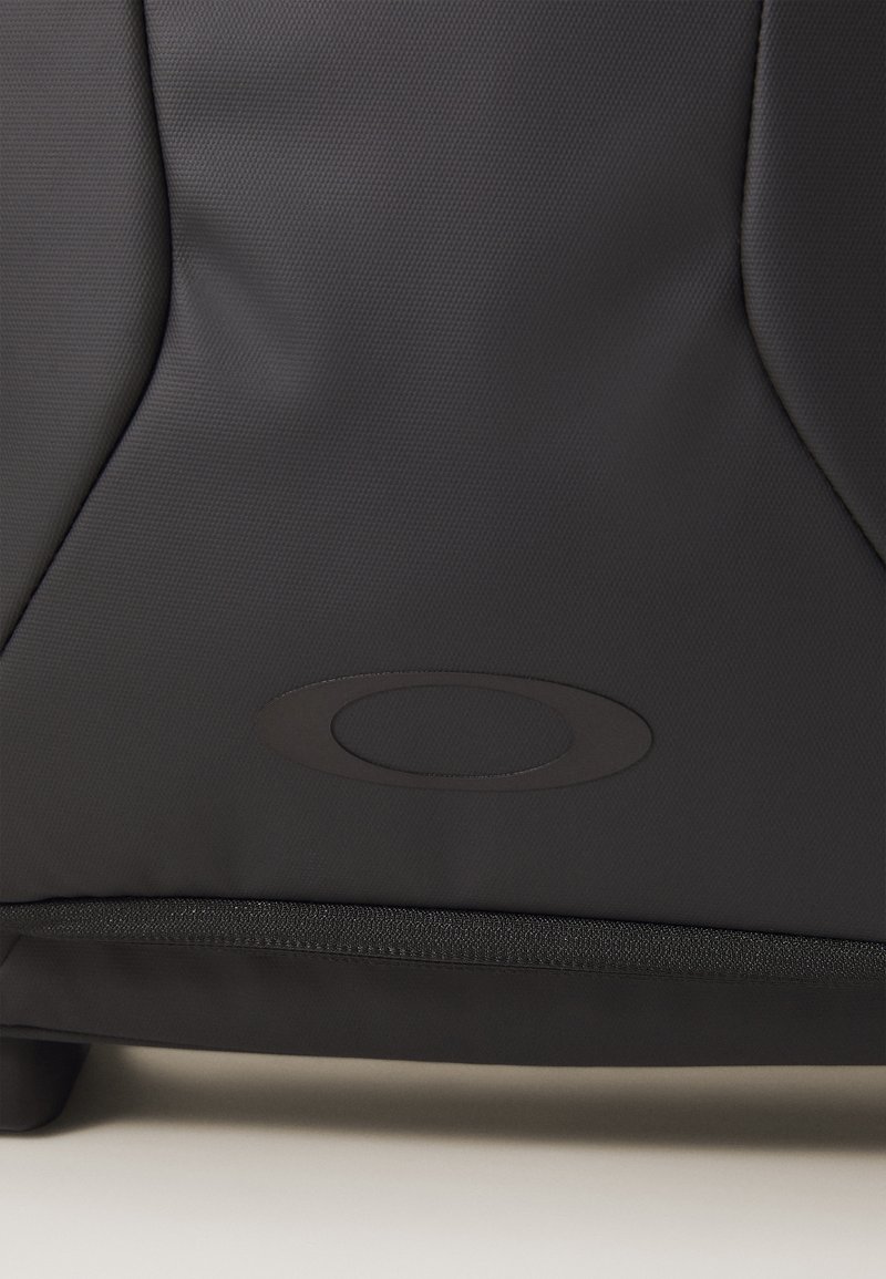 Svart ryggsäck i texturerat material med en slät dragkedja och en framträdande oval logotyp på framsidan.