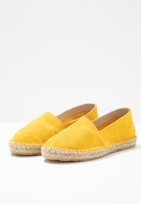 Espadrilles en daim jaune avec une semelle en jute. Conception à enfiler avec un bout arrondi et un minimum de coutures.
