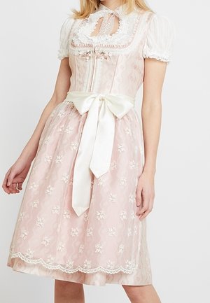 Kvinde iført en pink og hvid traditionel kjole med blonder, pufærmer og en stor satin sløjfe i taljen.