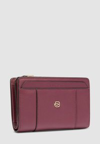 Portafoglio in pelle color bordeaux con tasca esterna, emblema del logo dorato sul davanti e dettagli di cuciture visibili su uno sfondo grigio chiaro.