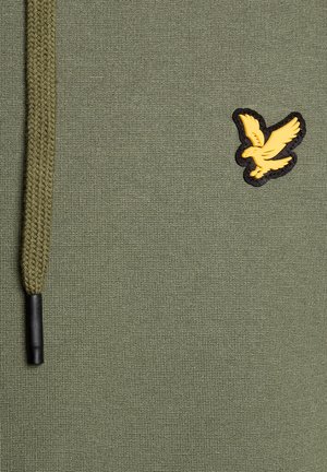 Groen textiel met een gevlochten trekkoord en een klein geel vogel-embleem met zwarte omlijning aan de rechterkant.