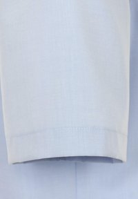 Lichtblauwe stof met een gladde textuur, met een net gestikte zoom op een shirt met korte mouwen. Eenvoudig en schoon ontwerp.