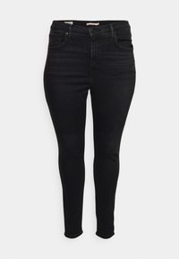 Jeans skinny negros de mezclilla, con una cintura de altura media, diseño de cinco bolsillos y un ligero desgaste. Textura suave con un hardware mínimo.