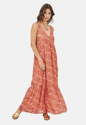 Vestido maxi con un patrón floral rojo, que presenta un escote en V, tirantes finos y una falda fluida con detalles fruncidos. Llevado con sandalias marrones.