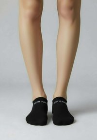 Chaussettes courtes noires avec bord côtelé, arborant le texte "SIXTH JUNE" en blanc. Texture lisse, conçues pour un ajustement près du pied.