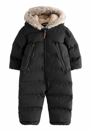 Combinaison noire pour bébé avec capuche doublée de fausse fourrure beige et de polaire, fermeture éclair frontale et poches poitrine zippées.