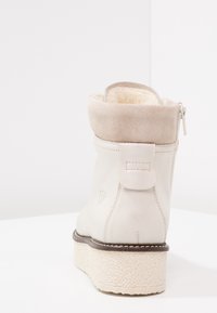 Białe skórzane botki za kostkę z miękkim beżowym zamszowym mankietem, bocznym zamkiem błyskawicznym i teksturowaną białą podeszwą, charakteryzujące się gładkim wykończeniem i minimalnymi akcentami.