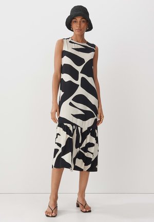 Sleeveless tiered dress made of lightweight fabric, featuring bold black abstract patterns on a cream background. Adjustable waistband detail.