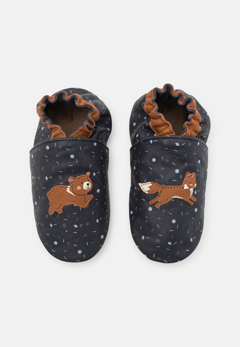 Chaussons en cuir de couleur bleu marine foncé avec une surface texturée, ornés d'un design d'ours et de renard, et un poignet élastique marron autour de l'ouverture.