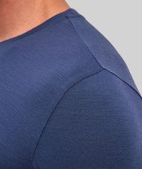 T-shirt blu navy con un primo piano della cucitura della spalla. Texture liscia con linee sottili, design aderente e dettagli di cuciture rinforzate.