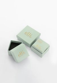 Mintgröna papperslådor, en något öppen, med guldfärgade bokstäver som står "elli premium." Svart inredning och logotyp på sidan av den mindre lådan.