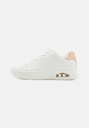 Baskets blanches avec une tige en cuir lisse, présentant un accent rose doré au niveau du talon et un amorti en air transparent dans la semelle.