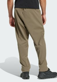 Khaki cargo bukser med afslappet pasform, strækstof, elastisk talje og tapered ben, båret med sorte trailsko.