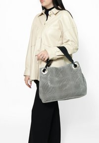 Borsa a tracolla grigia intrecciata con una finitura testurizzata, caratterizzata da accenti metallici circolari e una tracolla nera a contrasto. Forma strutturata, interno spazioso.