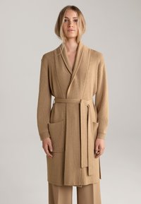 Beige gestrickte Strickjacke mit Schalkragen, langen Ärmeln, Bindegürtel und zwei Fronttaschen. Strukturiertes Gewebe mit glatter Oberfläche.