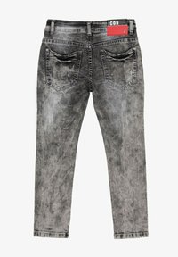 Jean skinny en denim gris avec une texture légèrement déchirée, dotés de deux poches arrière et d'une étiquette rouge sur la taille.
