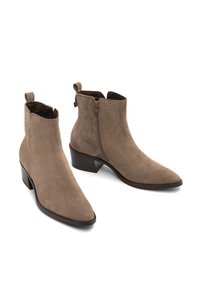 Un paio di stivaletti alla caviglia in suede taupe, con cerniere laterali, linguette per il pollice, tacco basso a blocco e punte appuntite su uno sfondo bianco.
