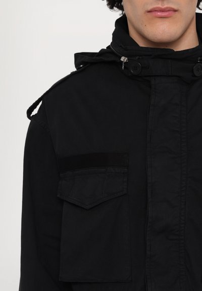 Zwarte jas met capuchon, met een ritssluiting en knoopsluiting aan de voorkant, twee borstzakken en een gestructureerde schouderaccent.