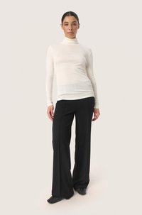 Lightweight, fitted white turtleneck paired with high-waisted black wide-leg trousers. Smooth texture, minimalistic design, no visible patterns.